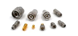 Multiple RF coaxial loads and connectors in various sizes and finishes on a white background.
