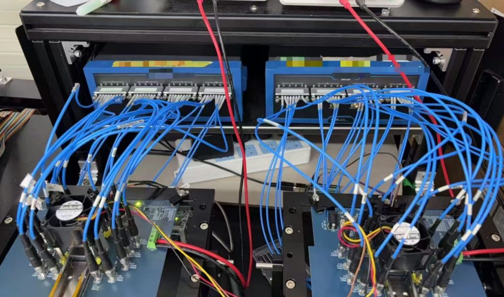 Rear view of a rack-mounted automated test system showing integration of multiple-port RF switch matrices, dense blue armored cable patching, and custom test boards for 110GHz mass production testing.